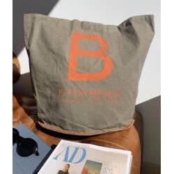 NR81 tote-taske i lærred – stående på stol med orange bogstavprint